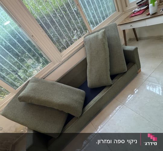 ספת בד ירוקה מפורקת מכריות במהלך תהליך ניקוי